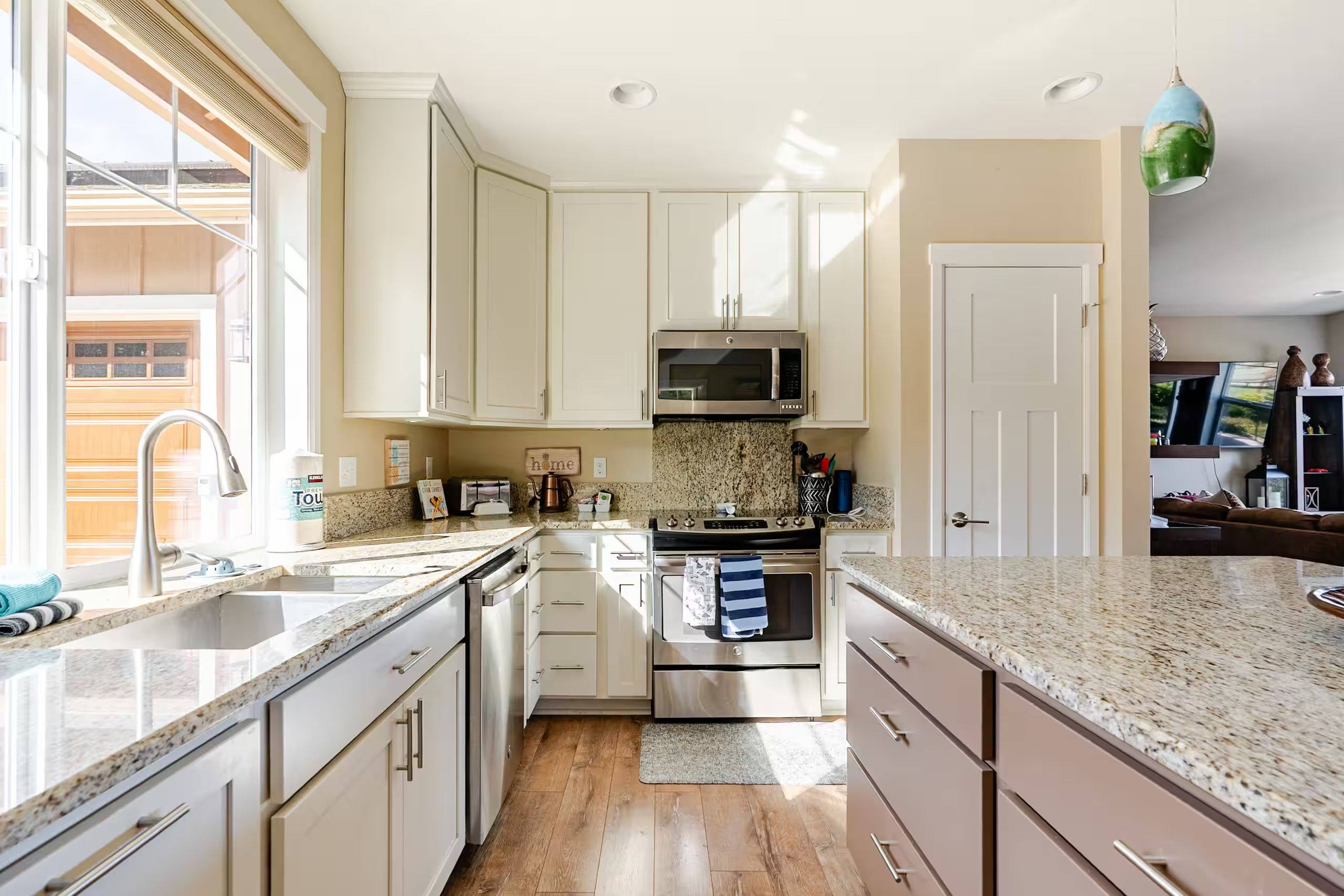 A modern kitchen with white cabinets, stainless steel appliances, and a granite countertop.