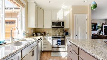 A modern kitchen with white cabinets, stainless steel appliances, and a granite countertop.