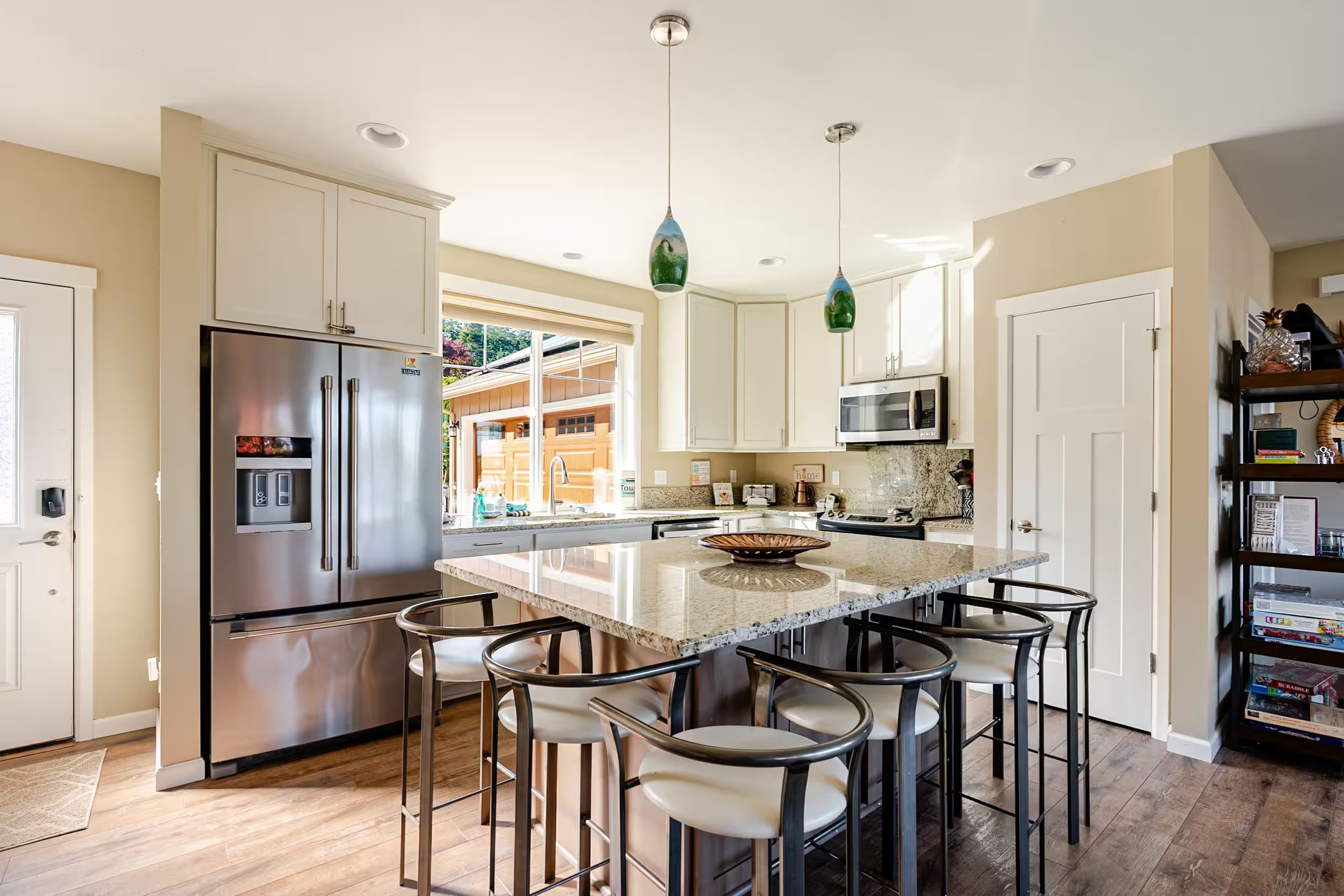 A modern kitchen with a central island, stainless steel appliances, and bar stools.
