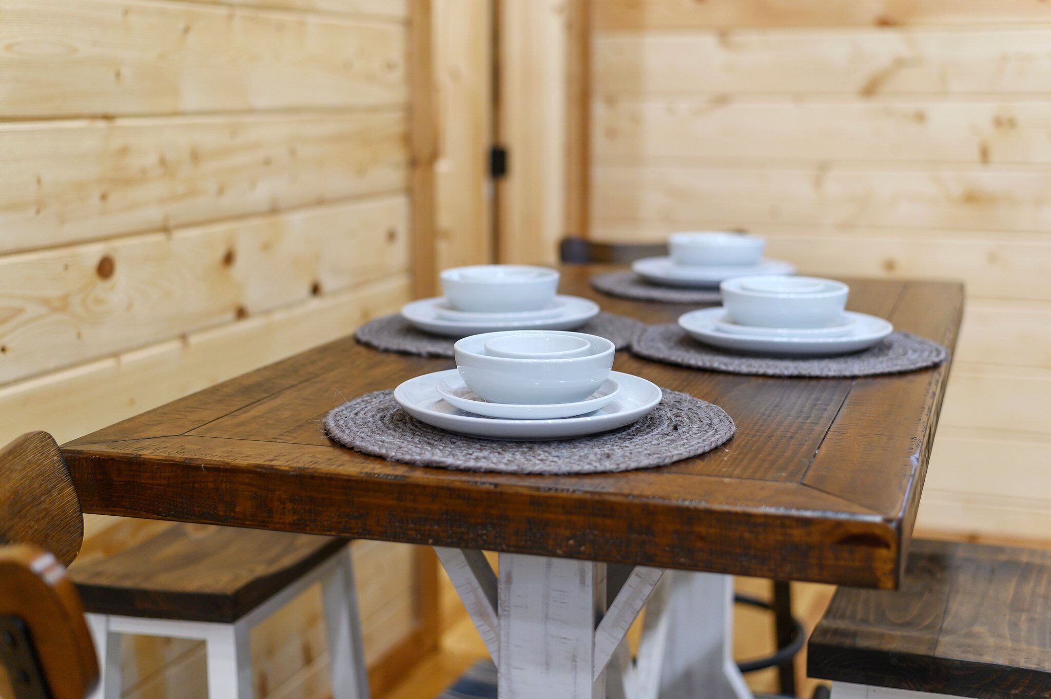 A wooden dining table with white plates and placemats.