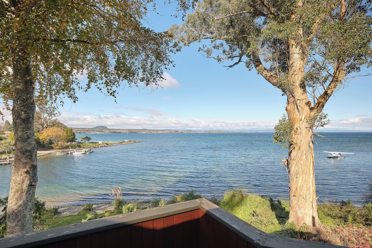 A coastal view with a wooden deck overlooking the sea, a small boat, and distant land.