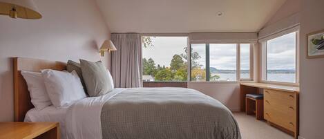 A bedroom with a bed, bedside tables, a desk, and a window with a view.