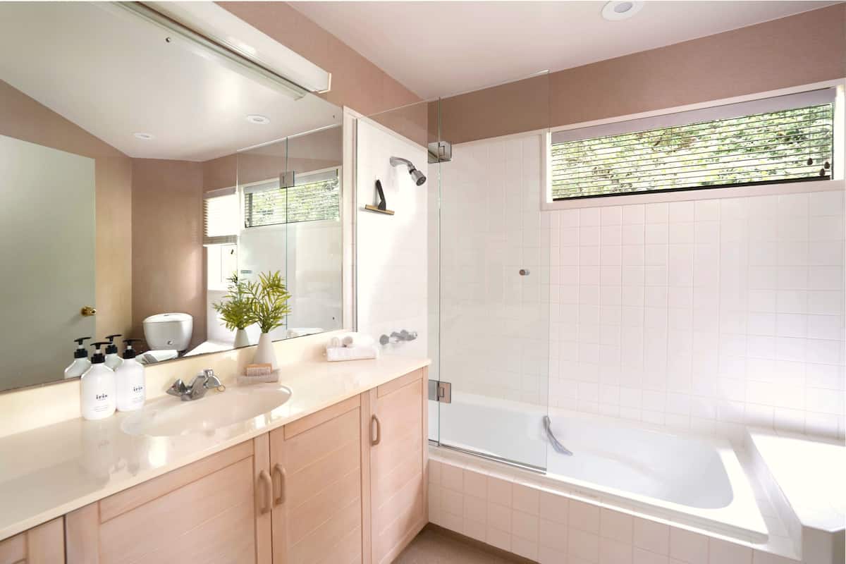 Enjoy an and luxurious bathing experience in this bathroom featuring a bathtub and glass-enclosed shower.