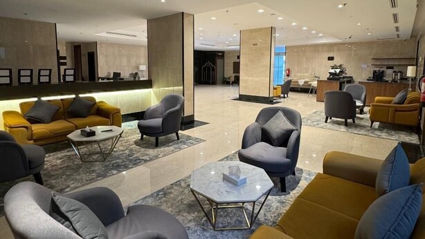 A spacious lobby with modern furniture, including sofas and armchairs, and a reception area with a counter. - Belvedere Hotel (Madinah)