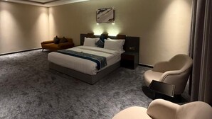 A modern hotel room with a large bed, a sofa, a chair, and a desk. - Belvedere Hotel (Madinah)