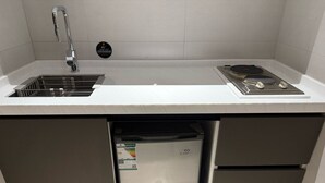 A compact kitchen with a stainless steel sink, a built-in stove, and a small refrigerator. - Belvedere Hotel (Madinah)