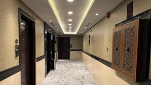 A hotel corridor with a carpeted floor, recessed ceiling lights, and a door on the left. - Belvedere Hotel (Madinah)