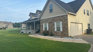 A two-story house with a stone facade, a covered porch, and a garage.