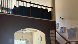 A spacious room with a pool table, a staircase, and a view of a balcony.