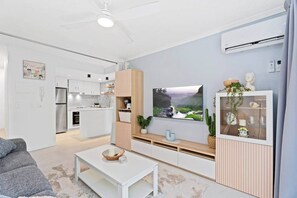 Un salon moderne avec un téléviseur à écran plat, une table basse et un canapé.