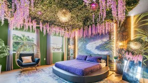 A bedroom with a round bed, hanging purple flowers, a hanging chair, and a mural of a forest path. - Glow Villa: 4K Cinema • Heated Pool & Spa • Lake • Sleeps 12 (Miami)