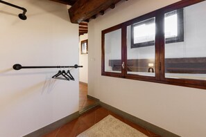 A hallway with a wooden ceiling, a window with a view, and a coat rack.