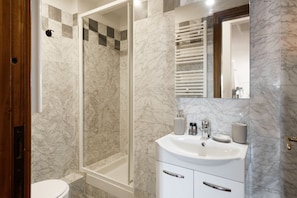 A bathroom with a shower, toilet, and sink.