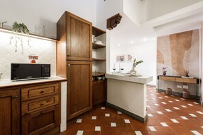 A kitchen with wooden cabinets, a microwave, and a tiled floor. - Apartments Florence -Faenza Terrace (Florence)