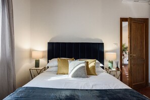 A hotel room with a bed, two bedside tables with lamps, a wooden door, and a view of the outside. - Apartments Florence -Faenza Terrace (Florence)