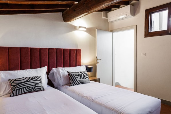 Quarto com duas camas, teto de madeira, espelho e porta.