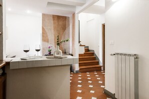 A modern kitchen with a central island, a staircase, and a radiator. - Apartments Florence -Faenza Terrace (Florence)