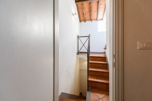 A staircase with a metal handrail and a wooden ceiling.