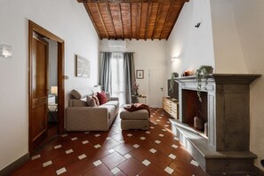 A living room with a fireplace, a sofa, a coffee table, and a patterned floor. - Apartments Florence -Faenza Terrace (Florence)