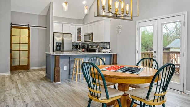 Een moderne keuken met witte kasten, een centraal eiland en een eethoek met vier stoelen.