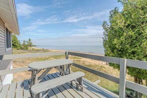 Eine Holzterrasse mit Picknicktischen mit Blick auf Strand und Meer.