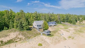 A beachfront property with a main house and a secondary building, connected by a wooden walkway.