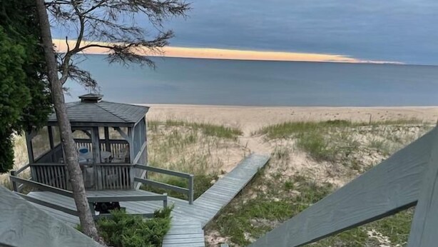 A wooden boardwalk leading to a beach with a small wooden structure.