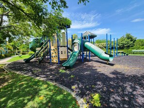 Explore a playground with slides and climbing elements set amidst a natural grassy area.