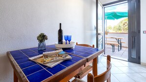 A dining area with a blue-tiled table, a bottle, and blue glasses.