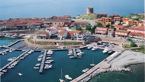 A coastal town with a marina, buildings with red roofs, and a castle-like structure.