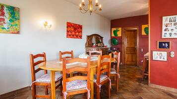 Un comedor con mesa y sillas de madera, una araña y obras de arte en la pared.