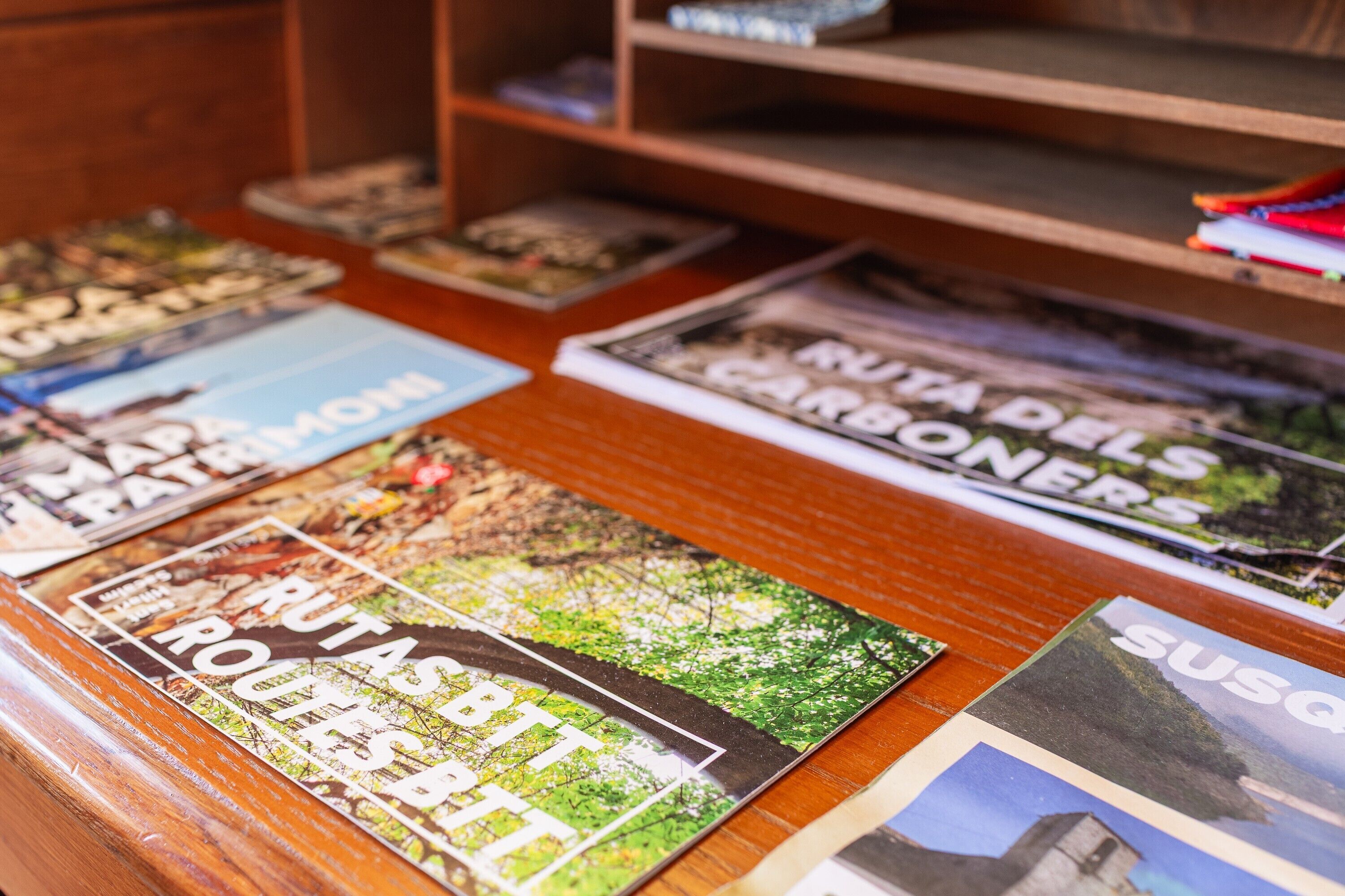 Una mesa de madera con varias revistas y folletos de viajes.