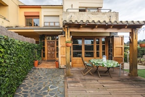 Una terraza de madera con una mesa y sillas, un sendero de piedra y una valla de madera.