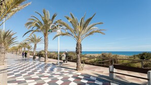 Un camí amb dibuixos de quadres, palmeres, bancs i vista al mar.