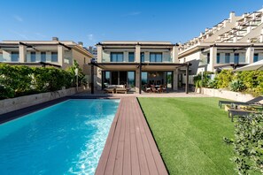 Un hôtel moderne doté d’une piscine, d’un patio et d’une pelouse bien entretenue.