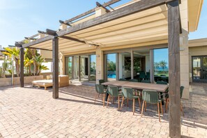 Une terrasse extérieure dotée d’une pergola en bois, d’une table à manger avec des chaises et d’un coin salon avec un canapé.