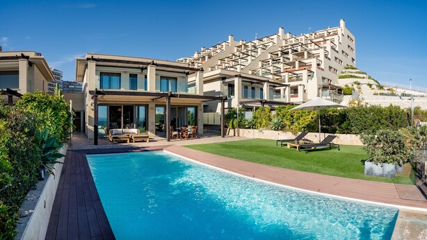 Hotel modern amb piscina, zona d'estar a l'aire lliure i vistes a una collada.