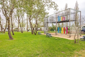 Un parc doté d’une structure d’escalade en métal, de bancs et d’arbres.