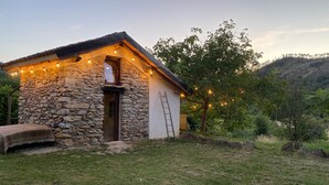 A stone building with a wooden door and a ladder leaning against it. - Casetta 'Delle Castagne' with Mountain View, Wi-Fi, and Air Conditioning (Casaleggio Boiro)