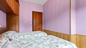 Un dormitorio con armario de madera, una puerta y una cama con ropa de cama floral.