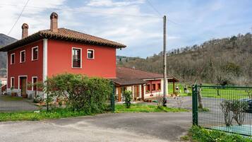 A red building with a tiled roof, a fenced yard, and a clear sky.