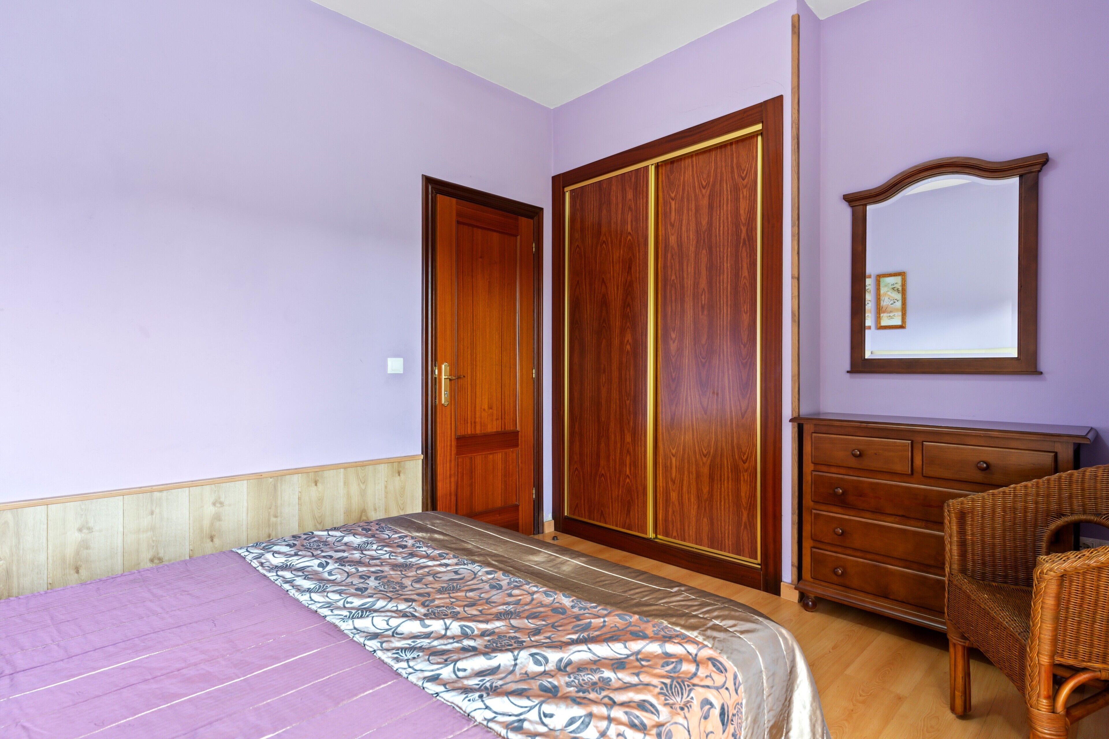 Une chambre à coucher comprenant un lit, une armoire, une commode et un miroir.