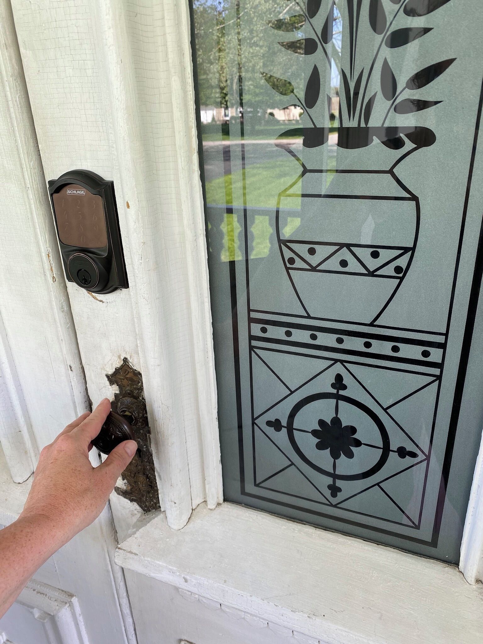 A hand reaching for a doorbell button on a white door.