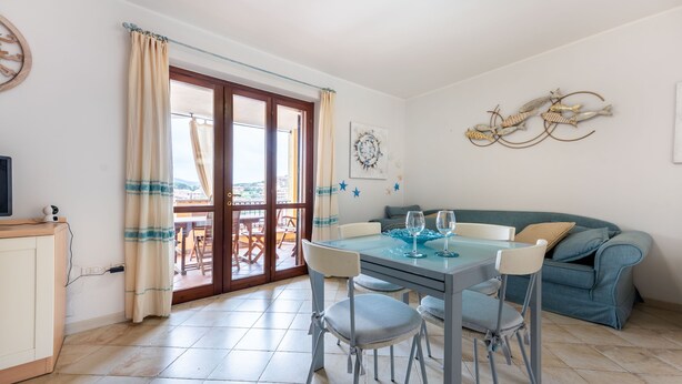 Un espace repas comprenant une table, des chaises et donnant sur l’extérieur grâce à une porte vitrée.
