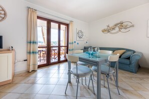 A dining area with a table, chairs, and a view through a glass door.