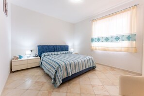 A bedroom with a bed, nightstands, and a window with curtains.
