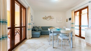 Une pièce comprenant une table à manger, des chaises, un canapé et un coin cuisine.