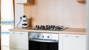 Une cuisine équipée d’une cuisinière à gaz, d’un four et d’une machine à café posée sur le plan de travail.