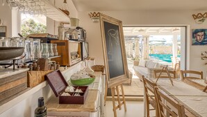 A kitchen with a chalkboard, wooden furniture, and a view of a pool.