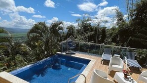 Une piscine sur le toit offrant une vue dégagée sur le paysage, entourée de chaises longues et d’une terrasse en bois.